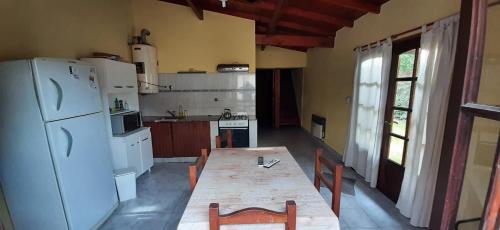 cocina con mesa y nevera blanca en Lleku lafken en Balneario Claromecó