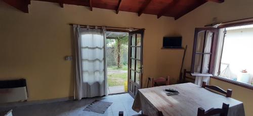 een eetkamer met een tafel en een glazen schuifdeur bij Lleku lafken in Balneario Claromecó