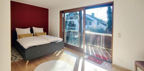 een slaapkamer met een bed en een groot raam bij Moderne Maisonette mit Garten in Unterschleißheim
