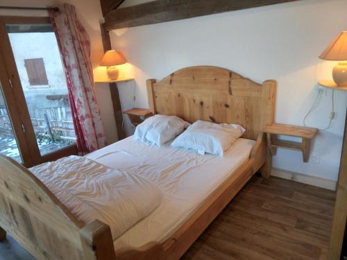 a bedroom with a wooden bed with two pillows at Chalet Balnéo Billard La Plagne Savoie Vue TOP in La Plagne Tarentaise