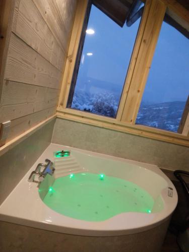 eine Whirlpool-Badewanne in einem Zimmer mit zwei Fenstern in der Unterkunft Chalet Balnéo Billard La Plagne Savoie Vue TOP in La Plagne Tarentaise
