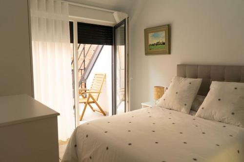 a bedroom with a bed and a balcony with a chair at Alojamiento NUEVO en el centro de León - Edificio RVM in León