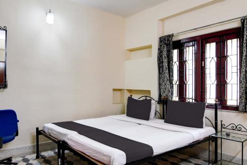 a bed in a room with two windows at OYO Simplex Guest House Behala in Kolkata