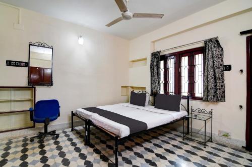 a bedroom with a bed and a blue chair at OYO Simplex Guest House Behala in Kolkata