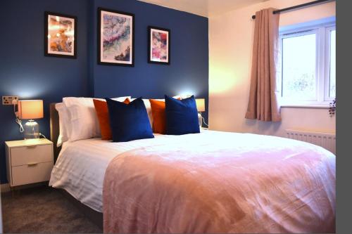 a bedroom with a bed with blue and orange pillows at Bard's Nest Scholars Cottage, Central Stratford, 5 mins walk to RSC in Stratford-upon-Avon