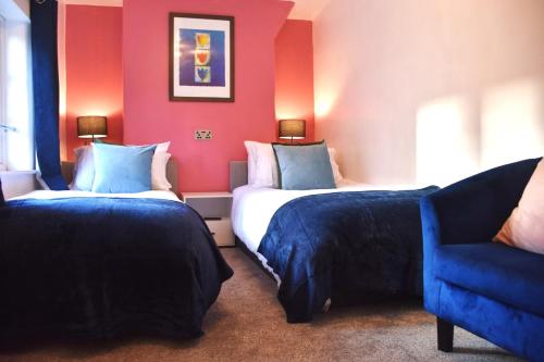 a hotel room with two beds and a blue chair at Bard's Nest Scholars Cottage, Central Stratford, 5 mins walk to RSC in Stratford-upon-Avon