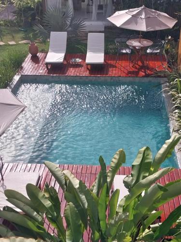 a swimming pool with two chairs and an umbrella at Casa Paula in Barra Grande