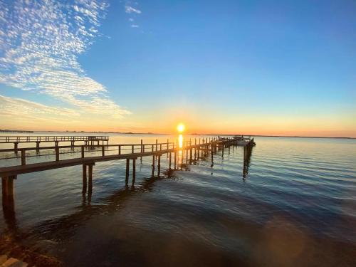 a pier with the sun rising over the water at Waterfront Resort Condo with Balcony Close to Beaches Free Bikes in Dunedin