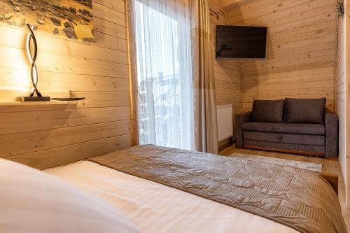 a bedroom with a bed and a window and a couch at Leśny Dwór Premium Chalets Zakopane in Murzasichle