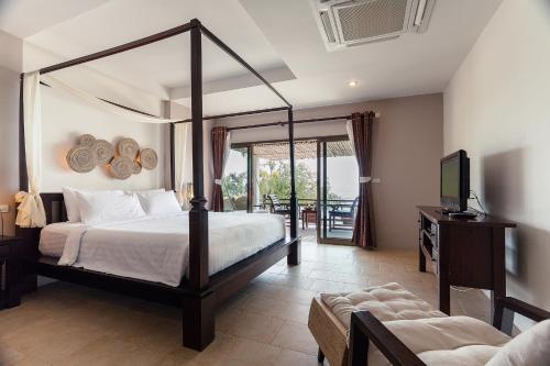 a bedroom with a canopy bed and a television at Sarikantang Resort & Spa, Koh Phangan in Haad Rin