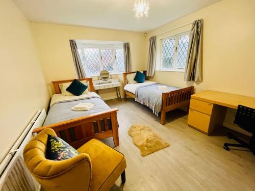 a bedroom with two beds and a chair and a desk at Vintage style Lodge In Windsor! Hot Tub! Sleeps 20 in Bray