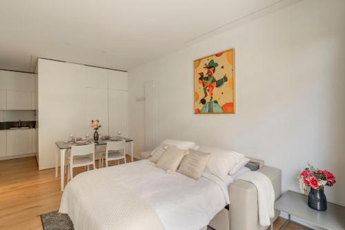 a white bedroom with a bed and a table at Lake Modern Suites - Free Parking in Lugano