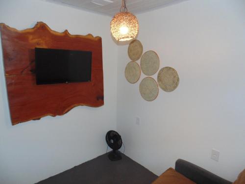 a living room with a tv and a mirror on the wall at Chalé Palhano Beach in São Miguel dos Milagres