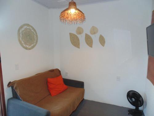 a living room with a couch and a chandelier at Chalé Palhano Beach in São Miguel dos Milagres
