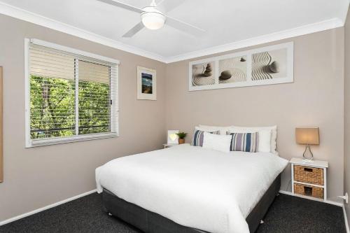 1 dormitorio con cama blanca y ventana en All Decked Out, en Kioloa