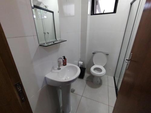 a white bathroom with a sink and a toilet at Xavi Studio in Bauru