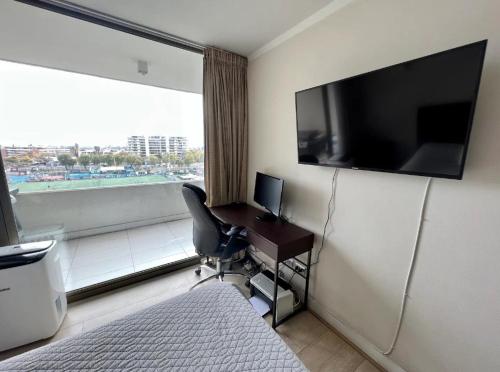 um quarto de hotel com uma secretária e uma grande janela em Apartamento cerca Mall Alto las Condes em Santiago