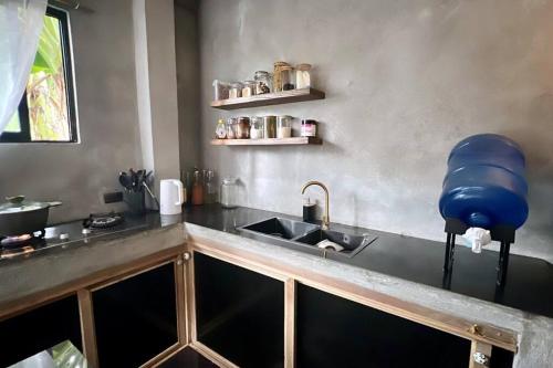 a kitchen with a sink and a blue container on the counter at 2 bedroom family house in Lodge in General Luna