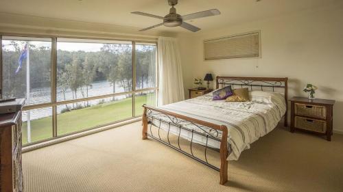 1 dormitorio con cama y ventana grande en Atlantis on lake conjola, en Yatte Yattah