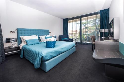 sypialnia z niebieskim łóżkiem i dużym oknem w obiekcie Hotel Arupinum w Rovinj