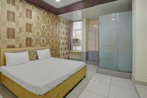 a bedroom with a bed and a glass shower at Super OYO Hotel Krishna Guest House & PG in Ludhiana