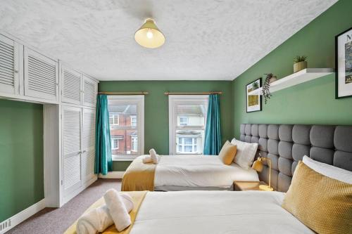 Buckinghamshire的住宿－Beautiful 2 bedroom house Free Parking, Aylesbury, Adrenham st，一间卧室设有两张床,拥有绿色的墙壁