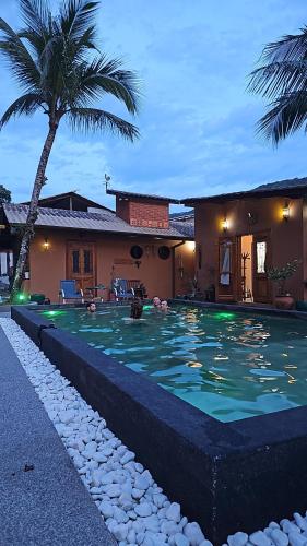 a swimming pool in front of a house with a palm tree at Hostel Txai Juquehy Suítes in Juquei