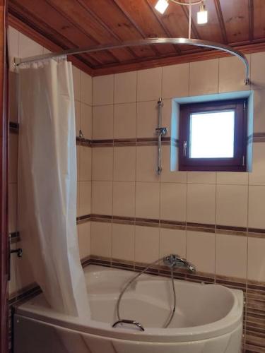 a bathroom with a tub with a shower curtain at Βίτσα Πετρόκτιστο Αρχοντικό "Ιόλη" με θέα Ζαγόρι in Vitsa