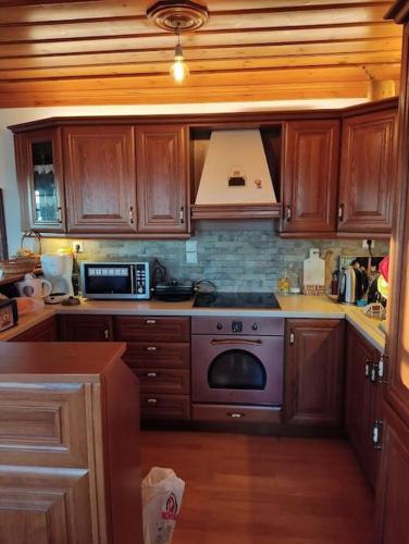 a kitchen with wooden cabinets and a stove top oven at Βίτσα Πετρόκτιστο Αρχοντικό "Ιόλη" με θέα Ζαγόρι in Vitsa