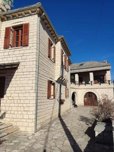 a large white brick building with red windows at Βίτσα Πετρόκτιστο Αρχοντικό "Ιόλη" με θέα Ζαγόρι in Vitsa