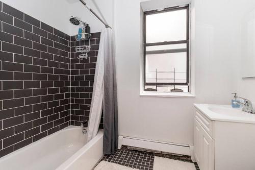 uma casa de banho com uma banheira branca e um lavatório. em 2Bed Bliss by Central Park North em Nova Iorque