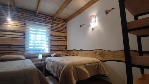 a bedroom with two beds and a window and a table at Cabaña Bosque Río in Pucón