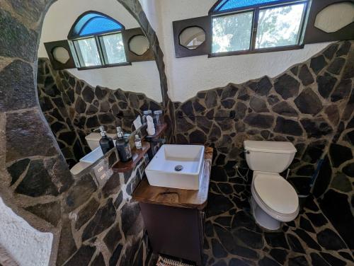 a bathroom with a toilet and a sink and windows at spirit of jungle lodge in Sámara