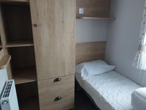 a small bedroom with a bed and a wooden cabinet at 208 Holiday Resort Unity Brean 3 bed entertainment passes included in Brean