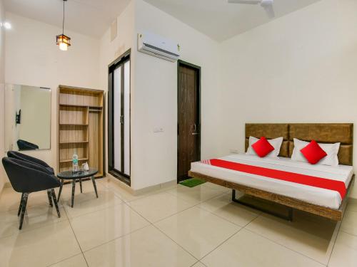 a bedroom with a bed with red pillows and a table at Super OYO Hotel Comfort Regency in Ludhiana