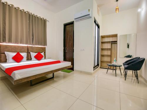 a bedroom with a bed with red pillows and a chair at Super OYO Hotel Comfort Regency in Ludhiana