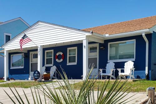 een blauw huis met witte stoelen en een Amerikaanse vlag bij Toes In The Sand in Atlantic Beach