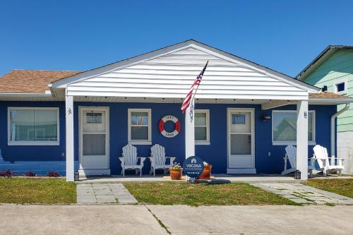 una casa azul con dos sillas de jardín y una bandera americana en Toes In The Sand, en Atlantic Beach