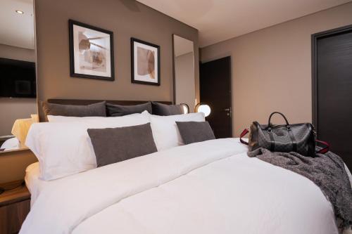 a bedroom with a large white bed with a purse on it at Condesa Luxury Apartments in Mexico City
