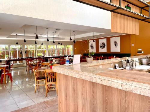 a restaurant with a bar with tables and chairs at Carlton Plaza Baobá in Taubaté