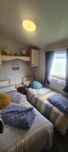 3 camas en una habitación con ventana en Bewles Caravan en Rhyl