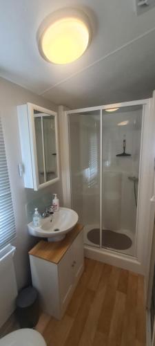 een badkamer met een douche, een wastafel en een toilet bij Bewles Caravan in Rhyl