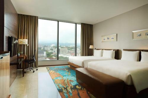 a hotel room with two beds and a large window at Hilton Bandung in Bandung