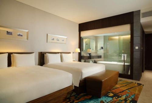 a hotel room with two beds and a bathroom at Hilton Bandung in Bandung