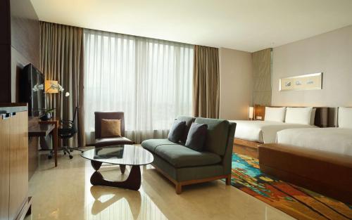 a hotel room with a bed and a couch and a table at Hilton Bandung in Bandung