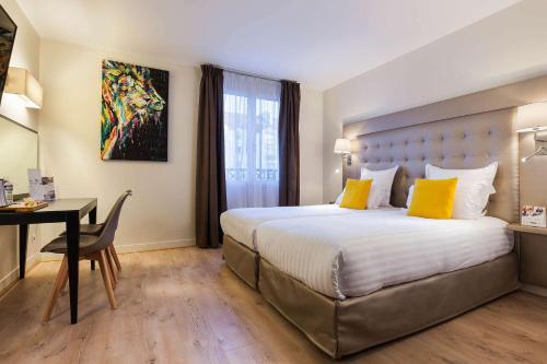 a hotel room with a bed with yellow pillows and a desk at Hôtel Quality Suites Maisons-Laffitte Paris Ouest in Maisons-Laffitte