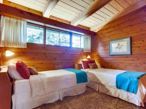 two beds in a room with wooden walls and windows at Point Loma Woods in San Diego