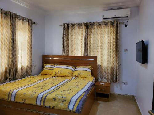 a bedroom with a bed with yellow sheets and curtains at TSOLID HOMES ( SHORTLET & APARTMENT) in Ibadan