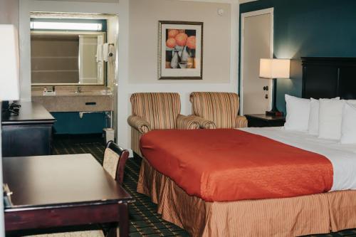 a hotel room with a bed and two chairs at Victorian Inn & Suites in Nacogdoches