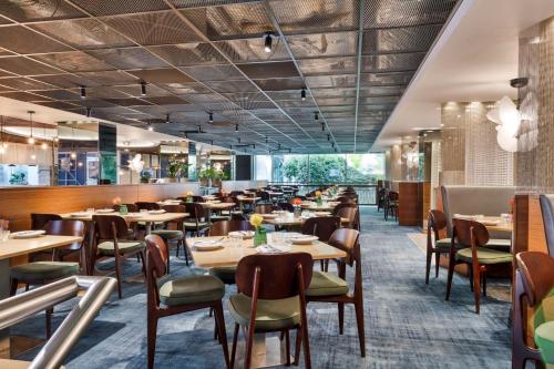 a restaurant with wooden tables and chairs at Radisson RED London Heathrow in Harmondsworth